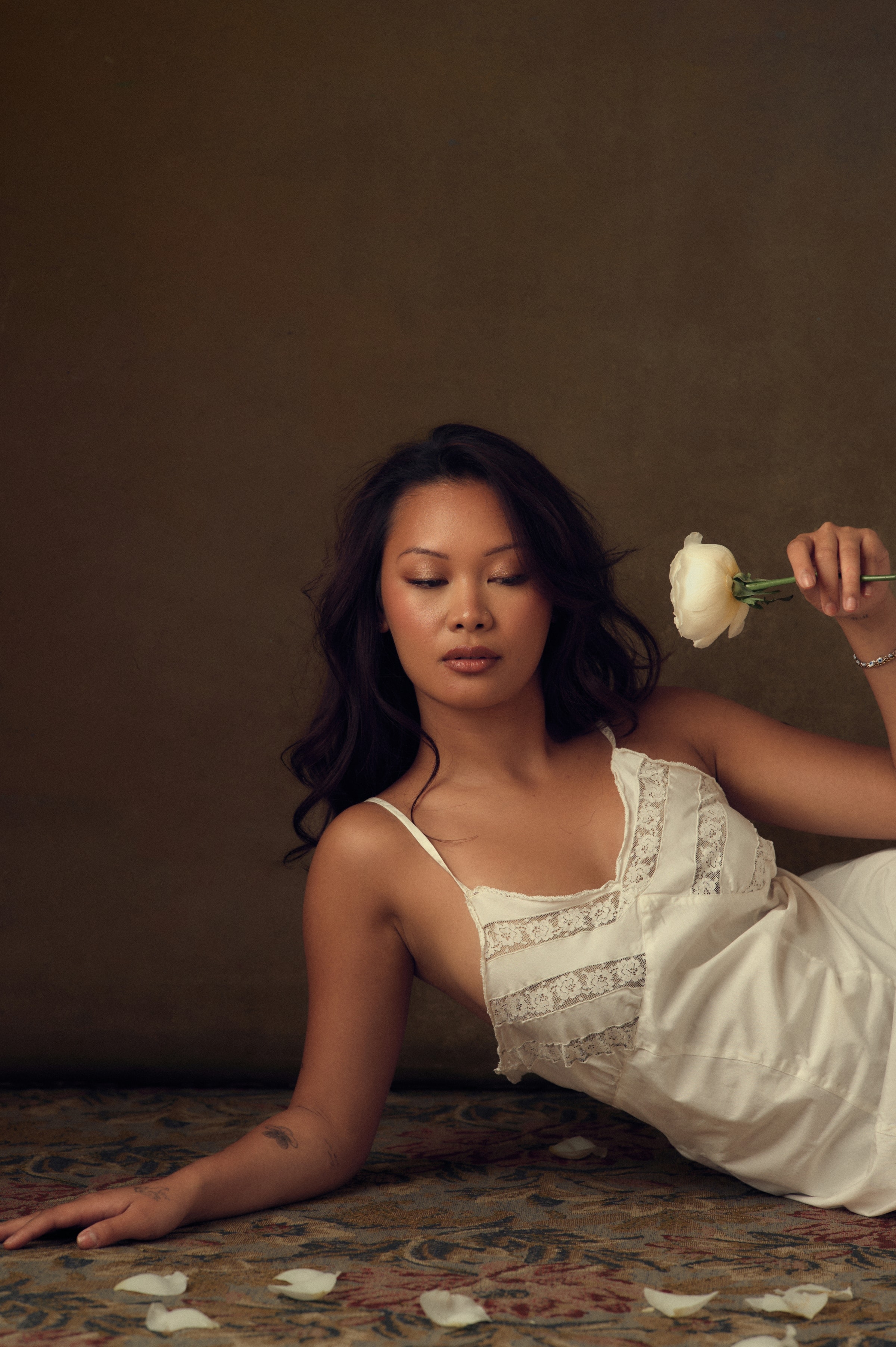 Editorial portrait reclining on the studio floor with a single rose