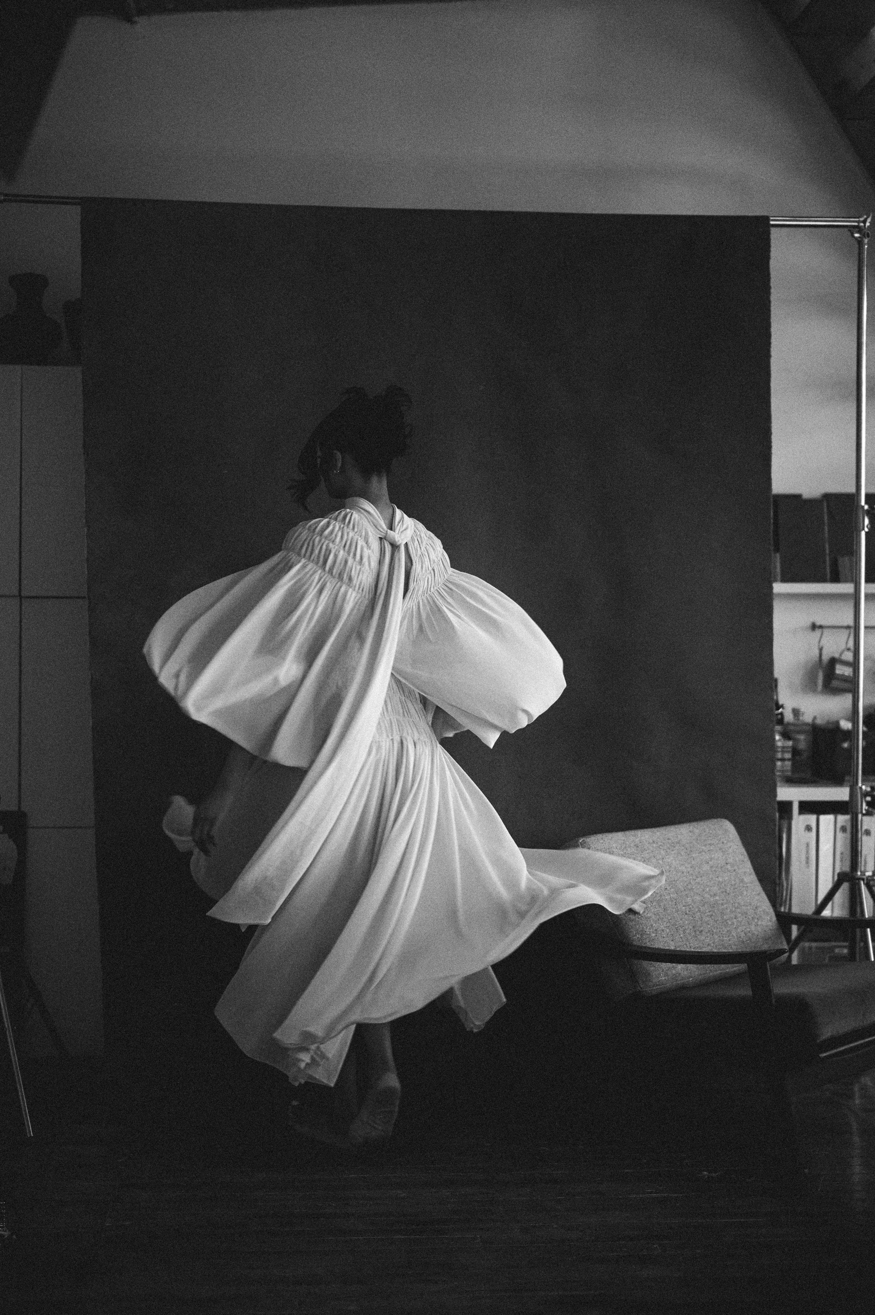 White dress in motion, long-exposure blur against a studio backdrop