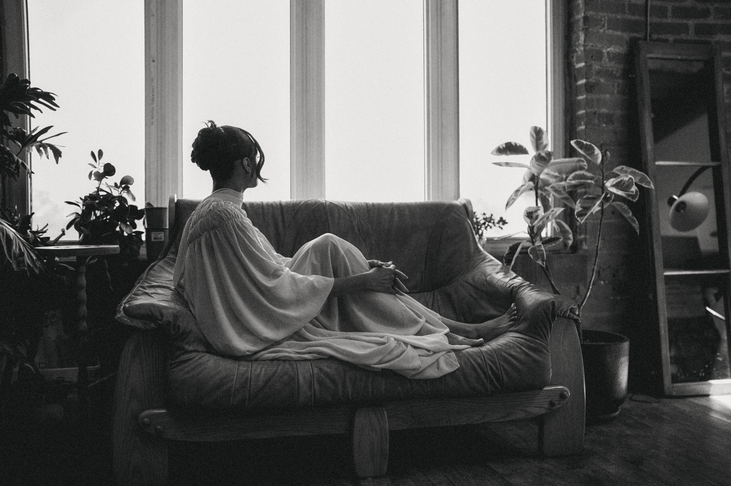 Bride reclining on a daybed by a loft window, black-and-white editorial portrait