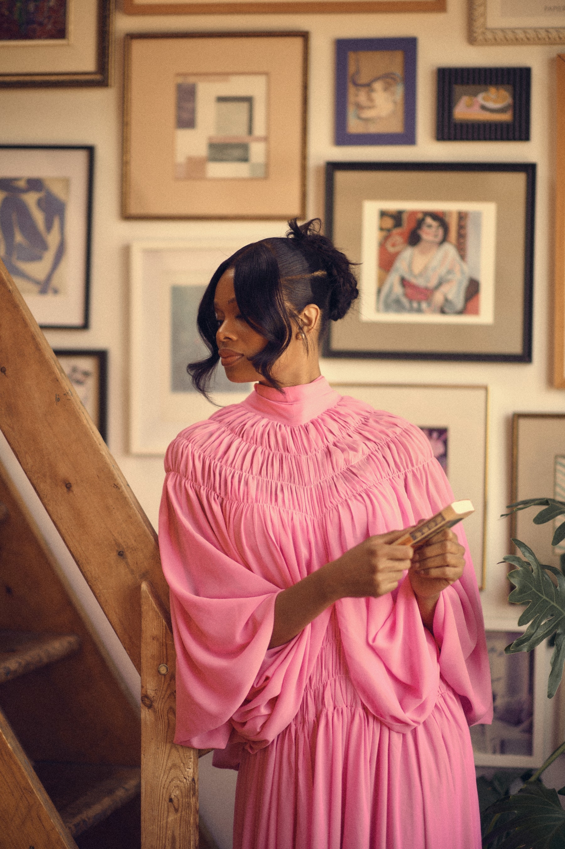 Editorial portrait in a pink gown before a gallery wall of framed art