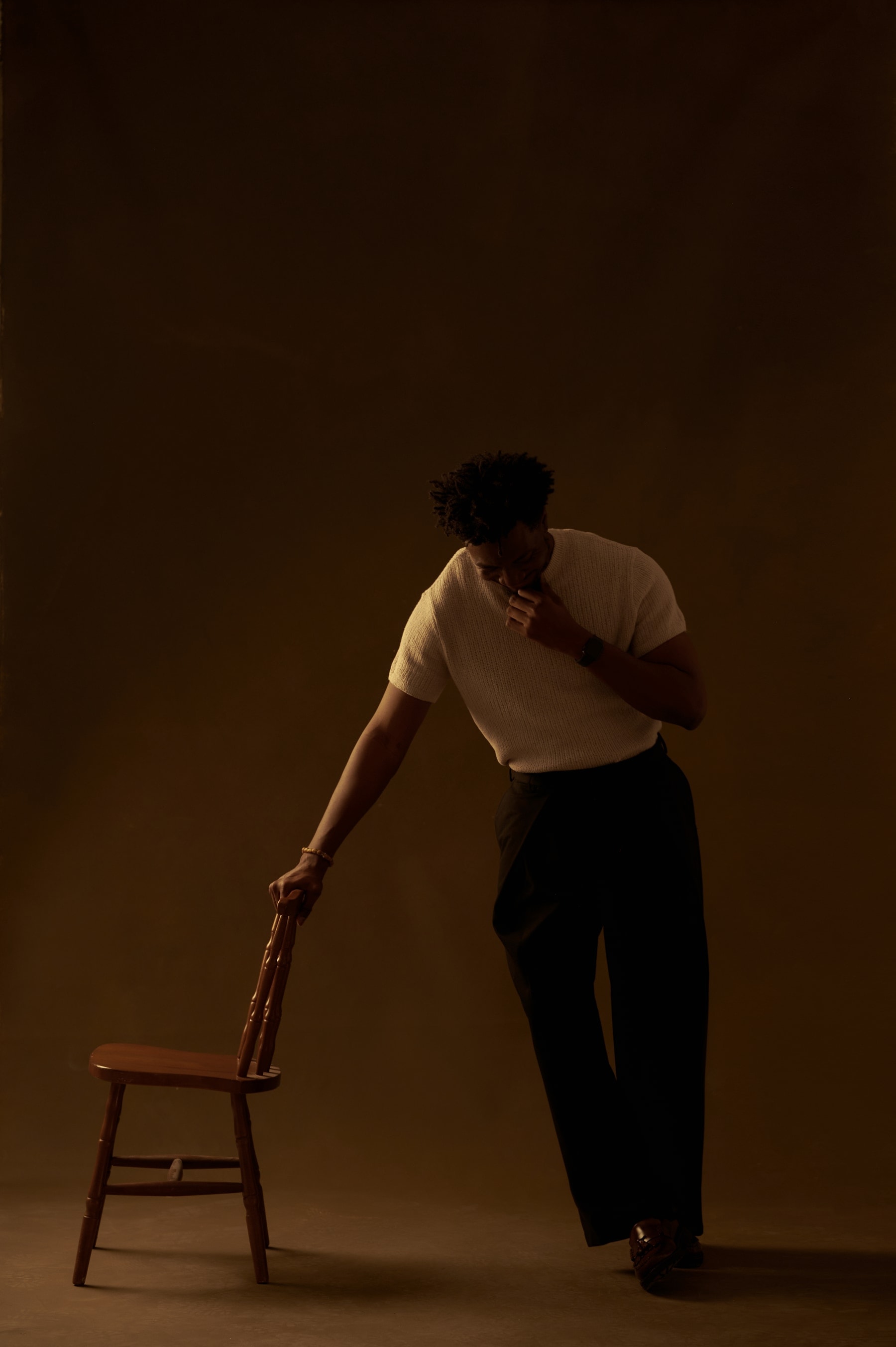 The photographer behind Fabolousbanji Studios, leaning on a wooden chair in a warm painterly studio