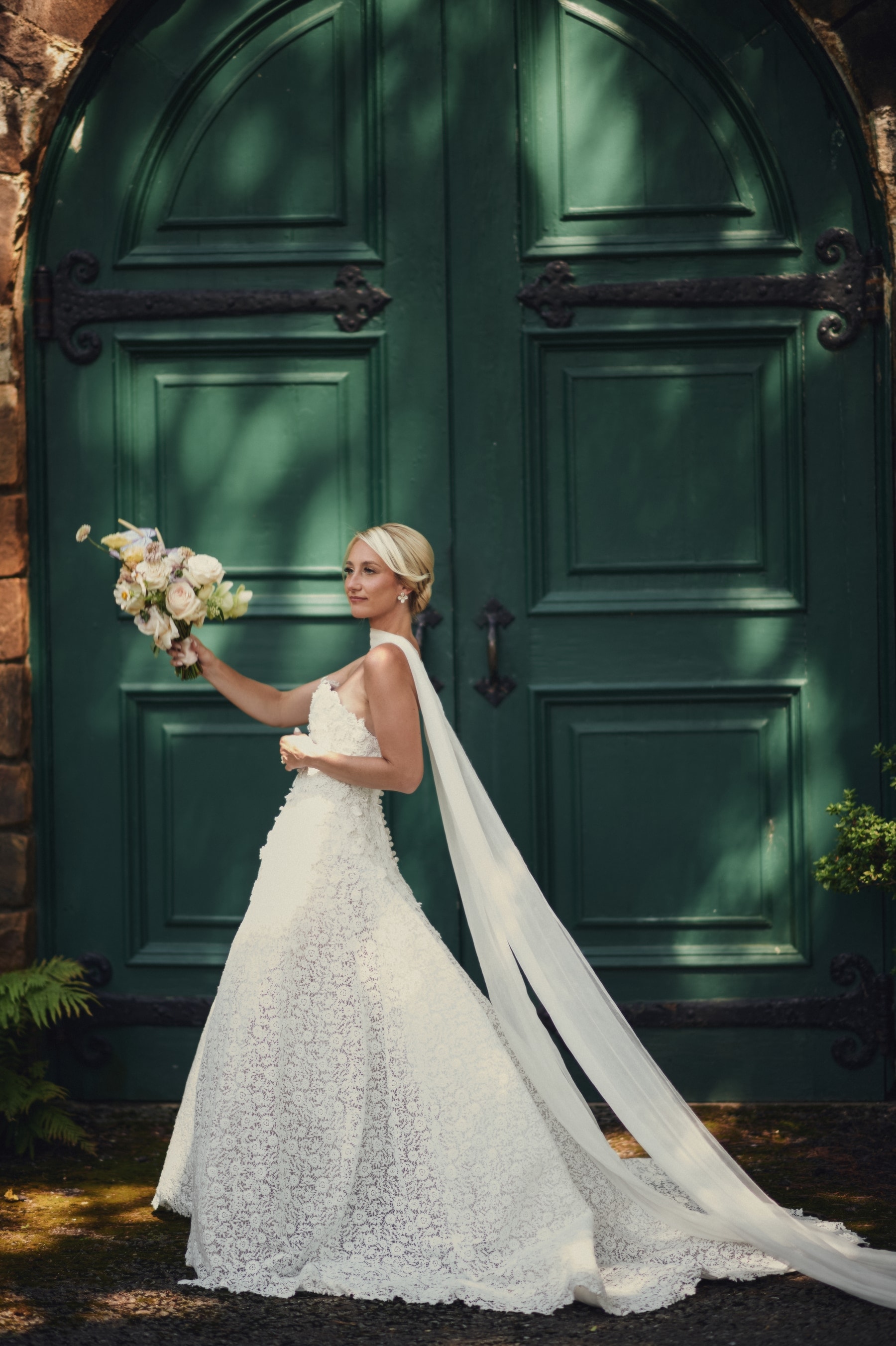 Bride laughing with her bouquet before deep-green chapel doors