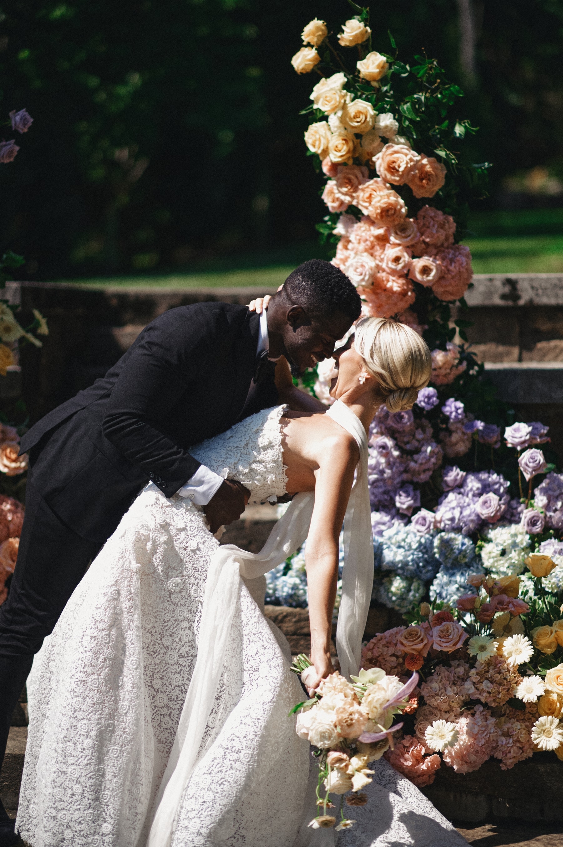 Groom lifting the bride before a wall of pastel florals