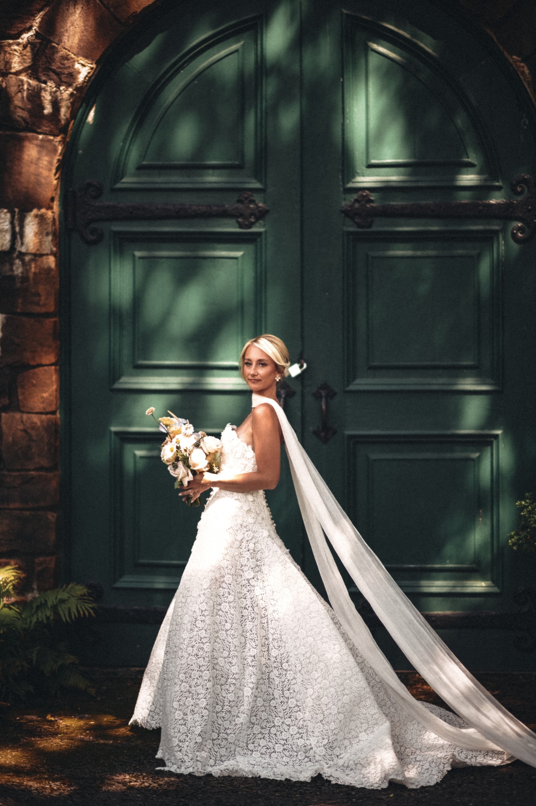 Christine glancing back at the green mansion doors, lace train sweeping the stone