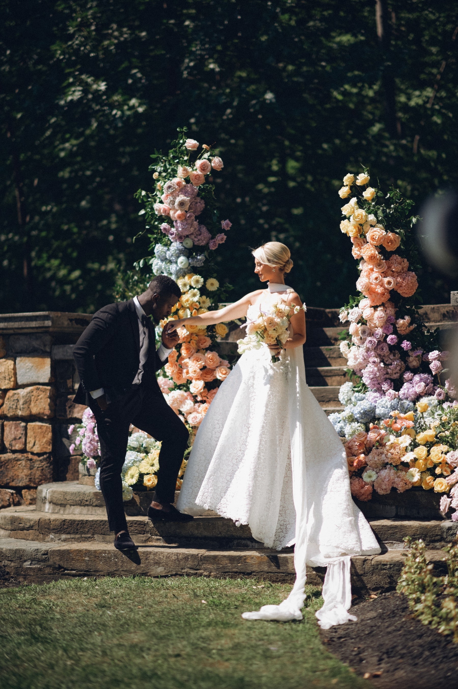 Kwame and Christine dancing between pastel flower pillars on the stone steps of Strong Mansion, Frederick, Maryland